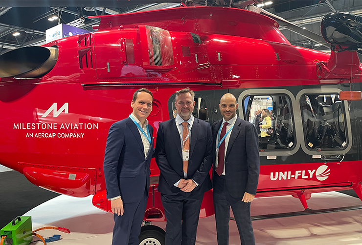Three men standing in front of a red helicopter